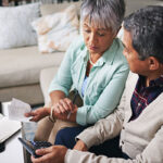 Older Latino couple looking at bills and making a budget together.